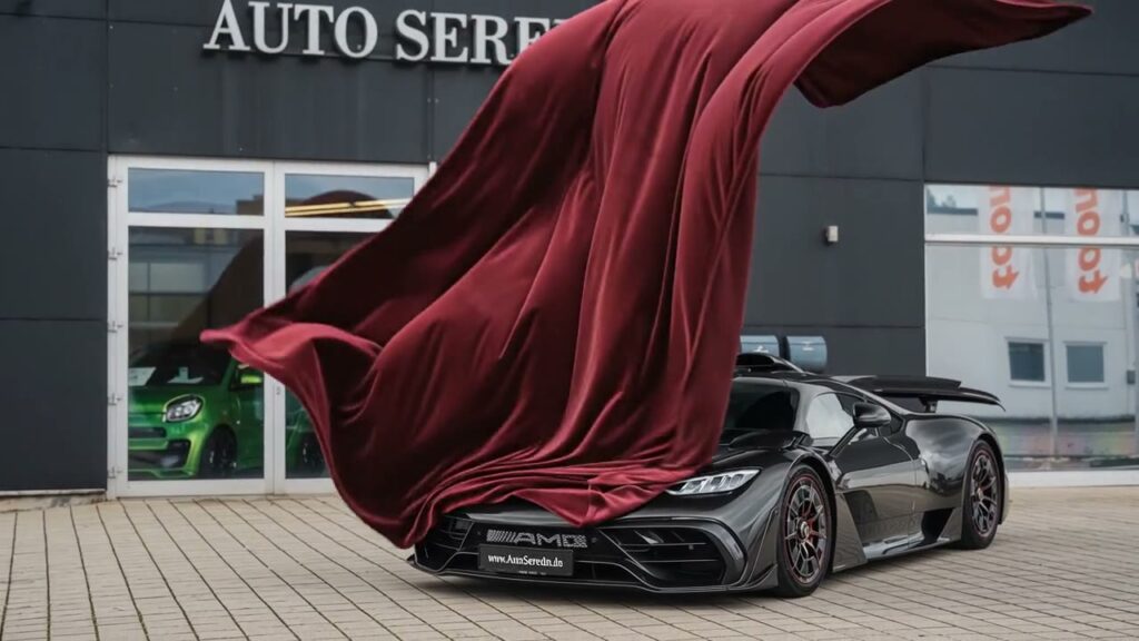 Mercedes-AMG ONE bei einer digitalen Inszenierung mit rotem Tuch vor einem Autohaus